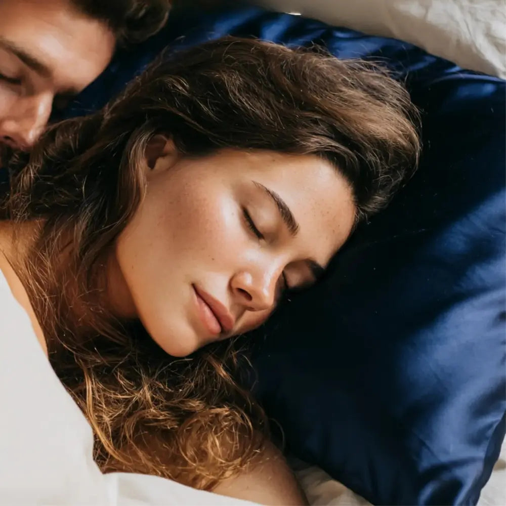 Woman sleeping on GLOWE Silk Pillowcase, silk that prevents frizzy hair, reduces breakage, and retains natural moisture