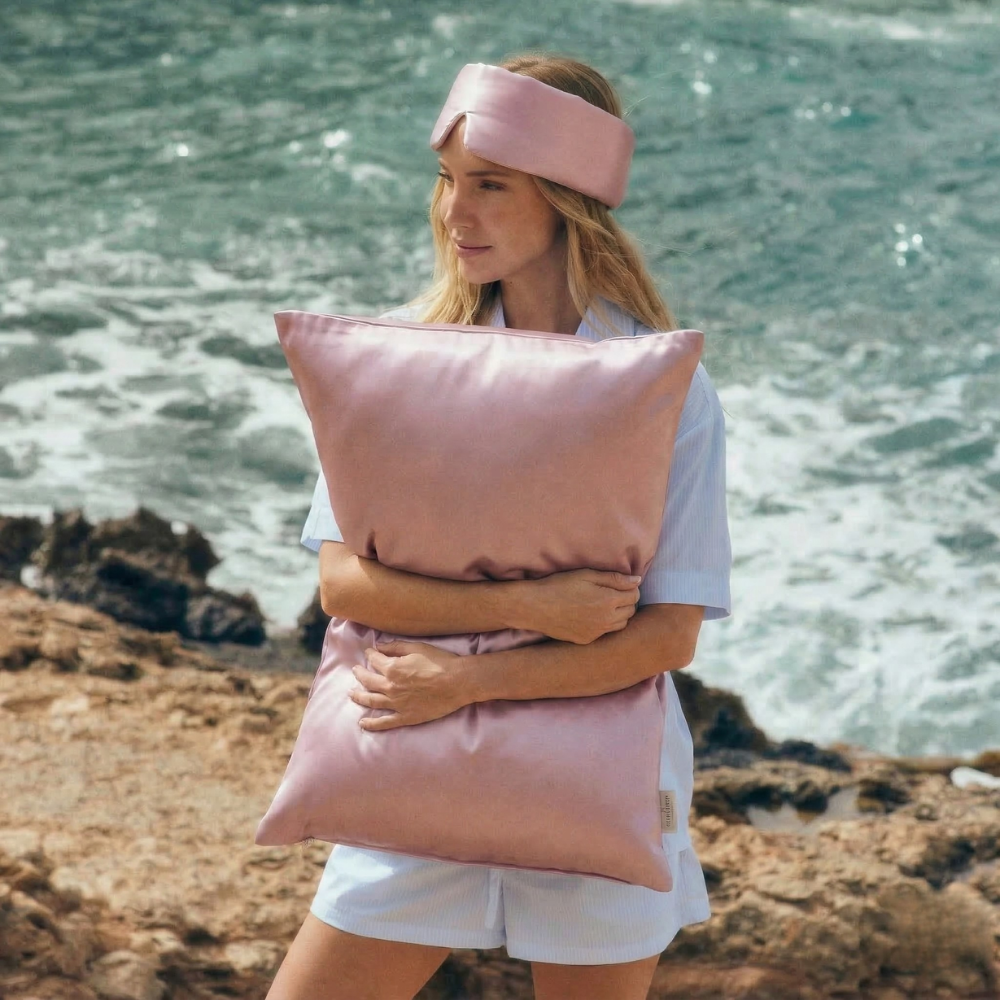 Woman holding GLOWE silk pillowcase in Soft Blush outdoors, lifestyle shot