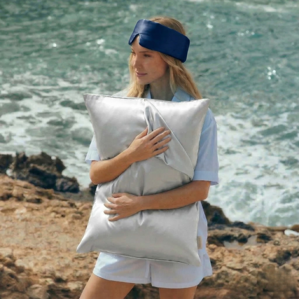 Woman holding GLOWE silk pillowcase outdoors, lifestyle shot