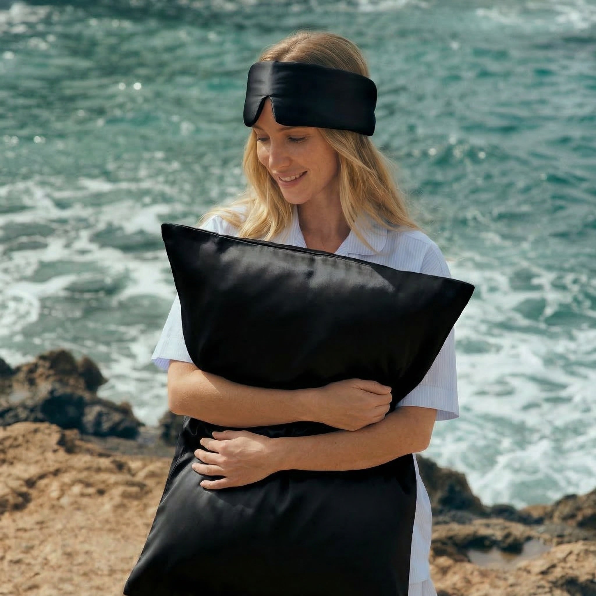 Woman holding GLOWE silk pillowcase in Midnight Black outdoors, lifestyle shot