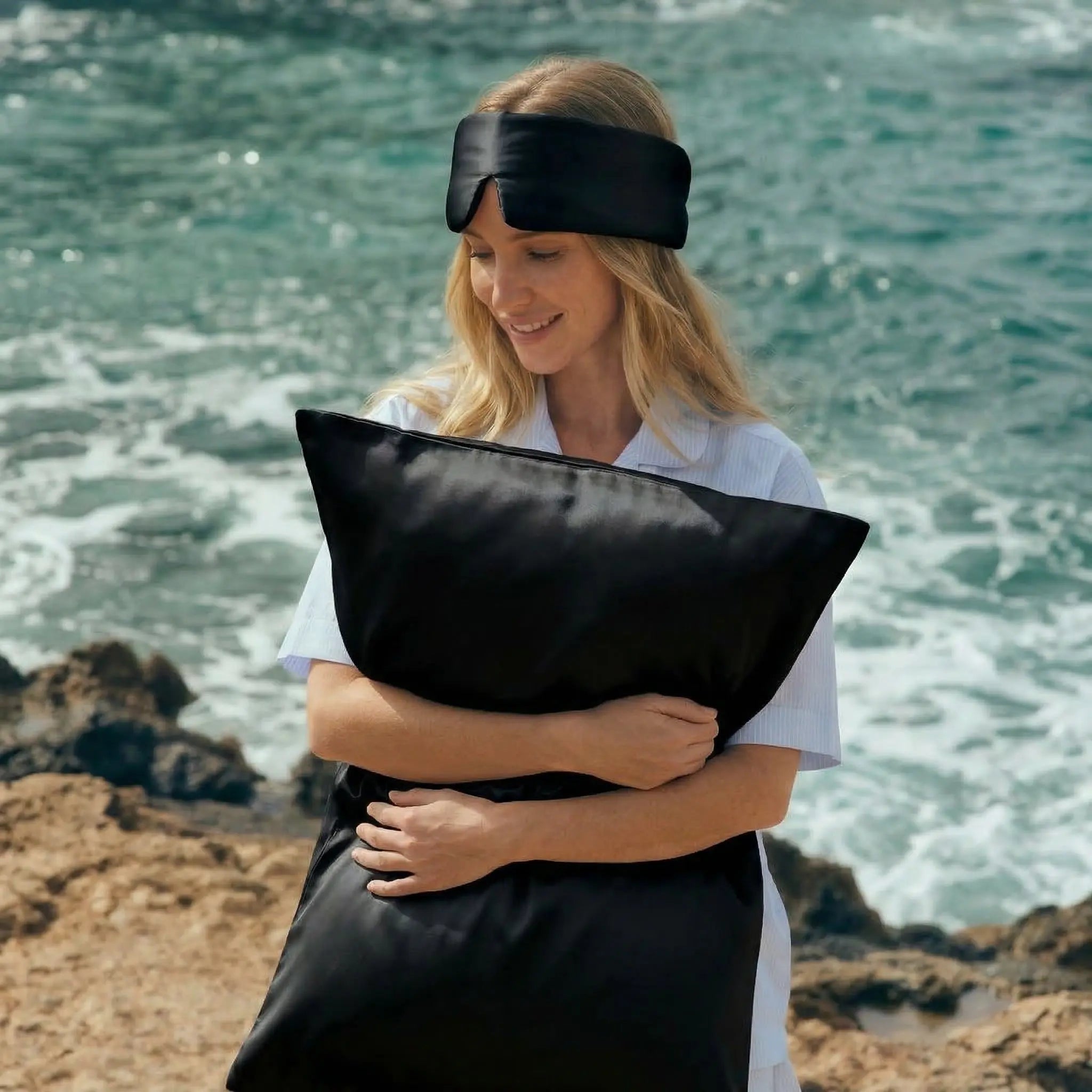 Woman holding GLOWE silk pillowcase in Midnight Black outdoors, lifestyle shot