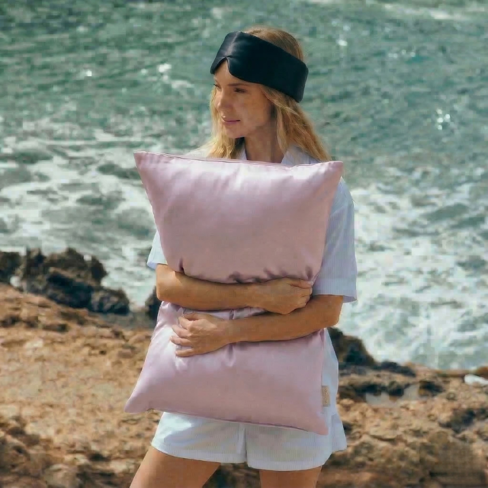 Woman holding GLOWE silk pillowcase outdoors, lifestyle shot